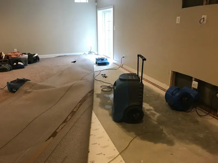 Dehumidifier and air mover drying a room with the carpet pulled back