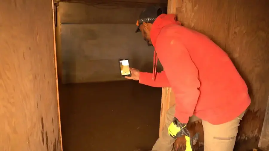 Technician taking moisture readings on a wood-paneled wall in a Germantown home