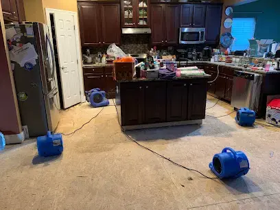 Air movers drying a kitchen floor after an appliance leak