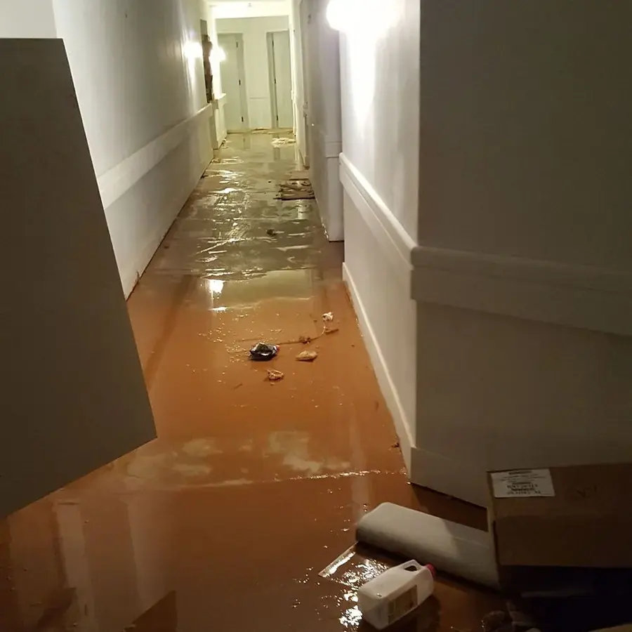 Muddy flood water covering a hallway floor with debris
