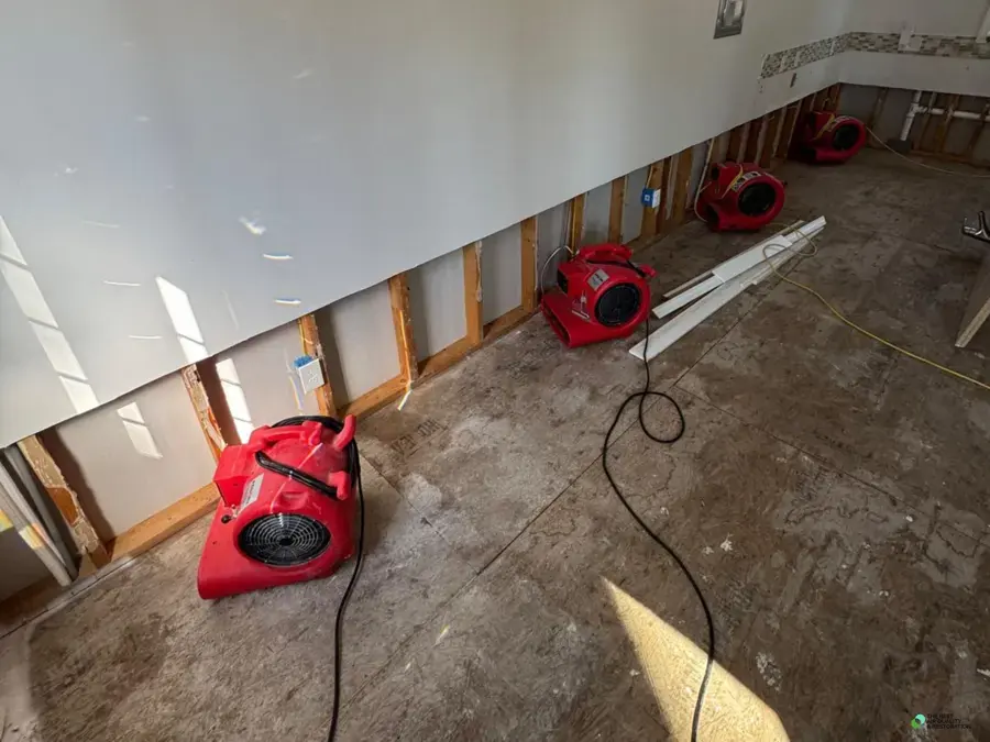 Air movers lined along flood-cut walls drying the floor and framing