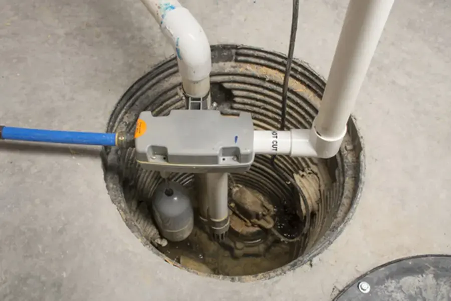 Sump pit with its pump, float and discharge pipe set in a basement floor